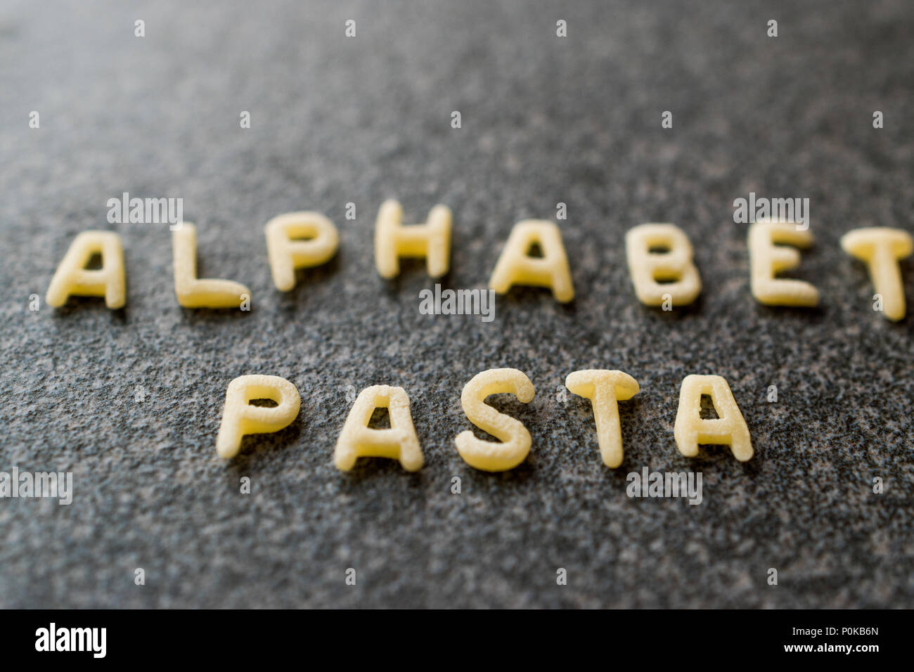Raw Alphabet Pasta is Written with Letters on Granit Grey Surface