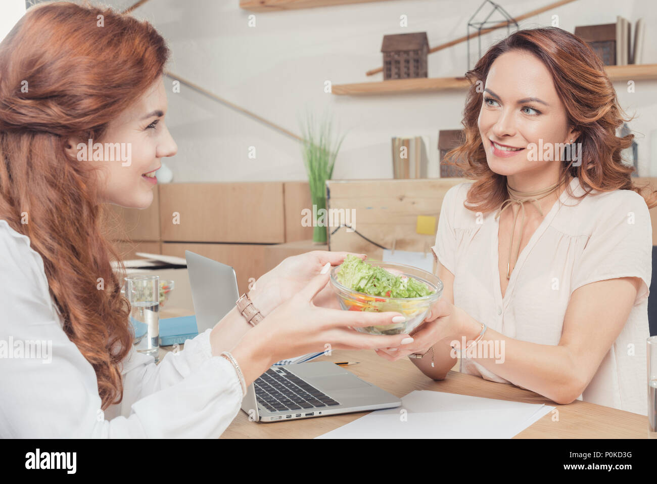 beautiful young coworkers sharing healthy salad at office Stock Photo