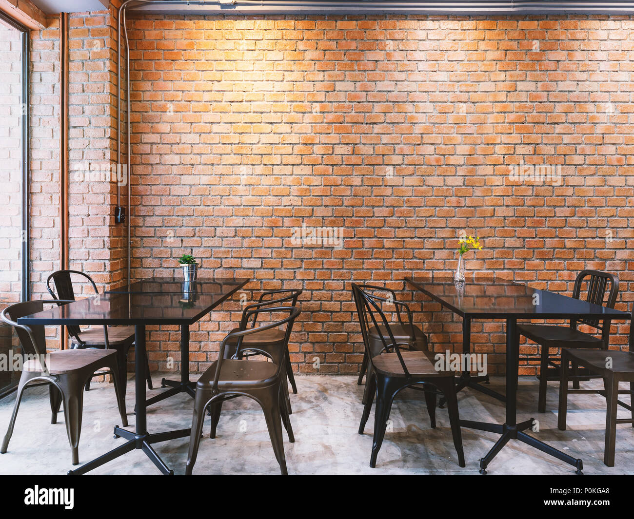 Modern cafe in loft style, black table set for coffee with brick wall