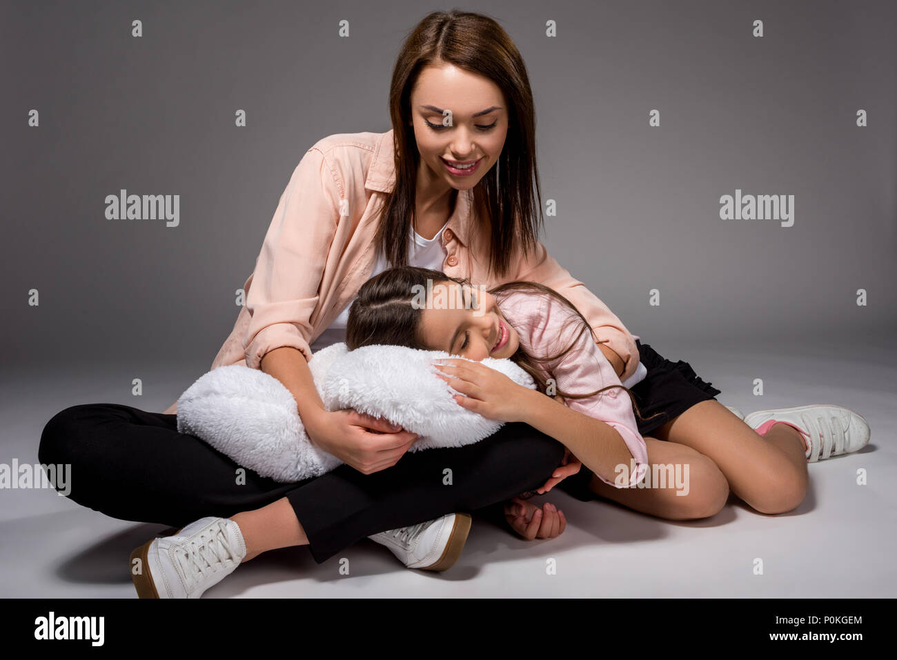 Daughter Sleeping On A Pillow On Mothers Legs On Gray Stock Photo