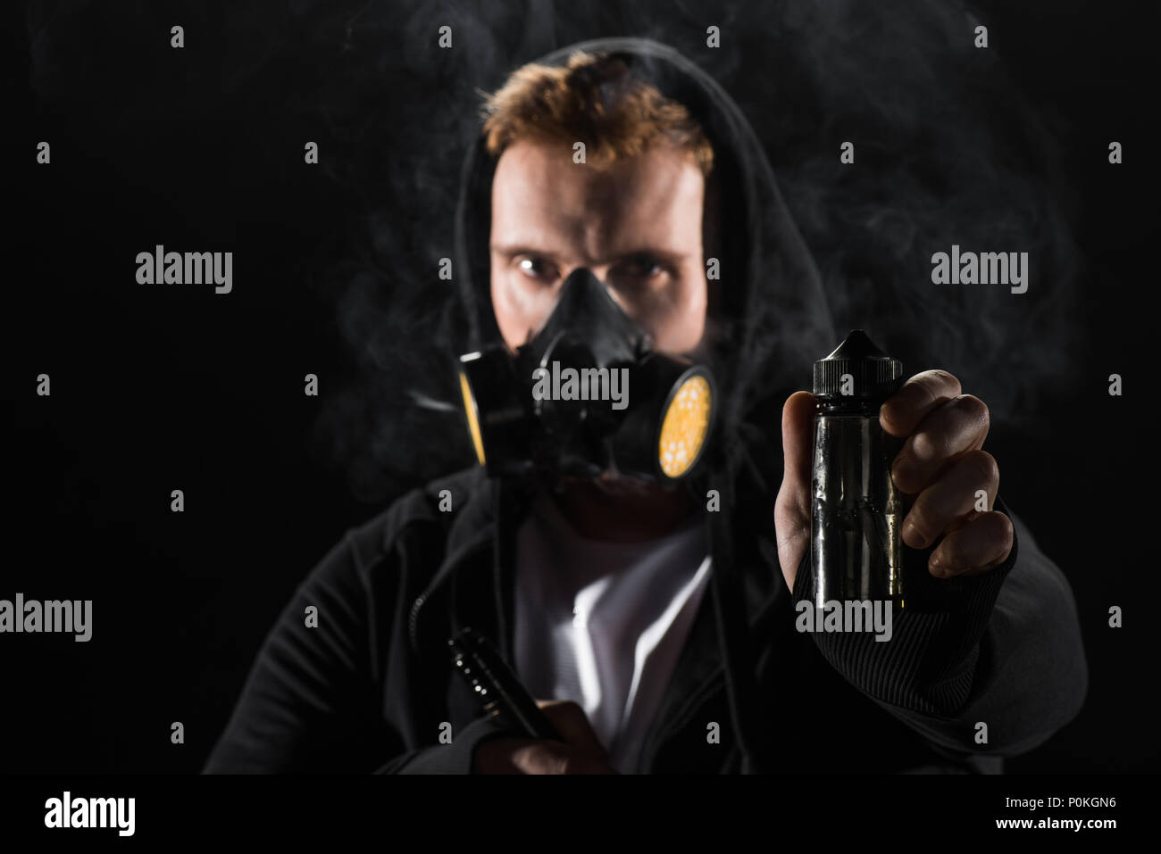 Man wearing protective filter mask smoking electronic cigarette showing  E-liquid Stock Photo