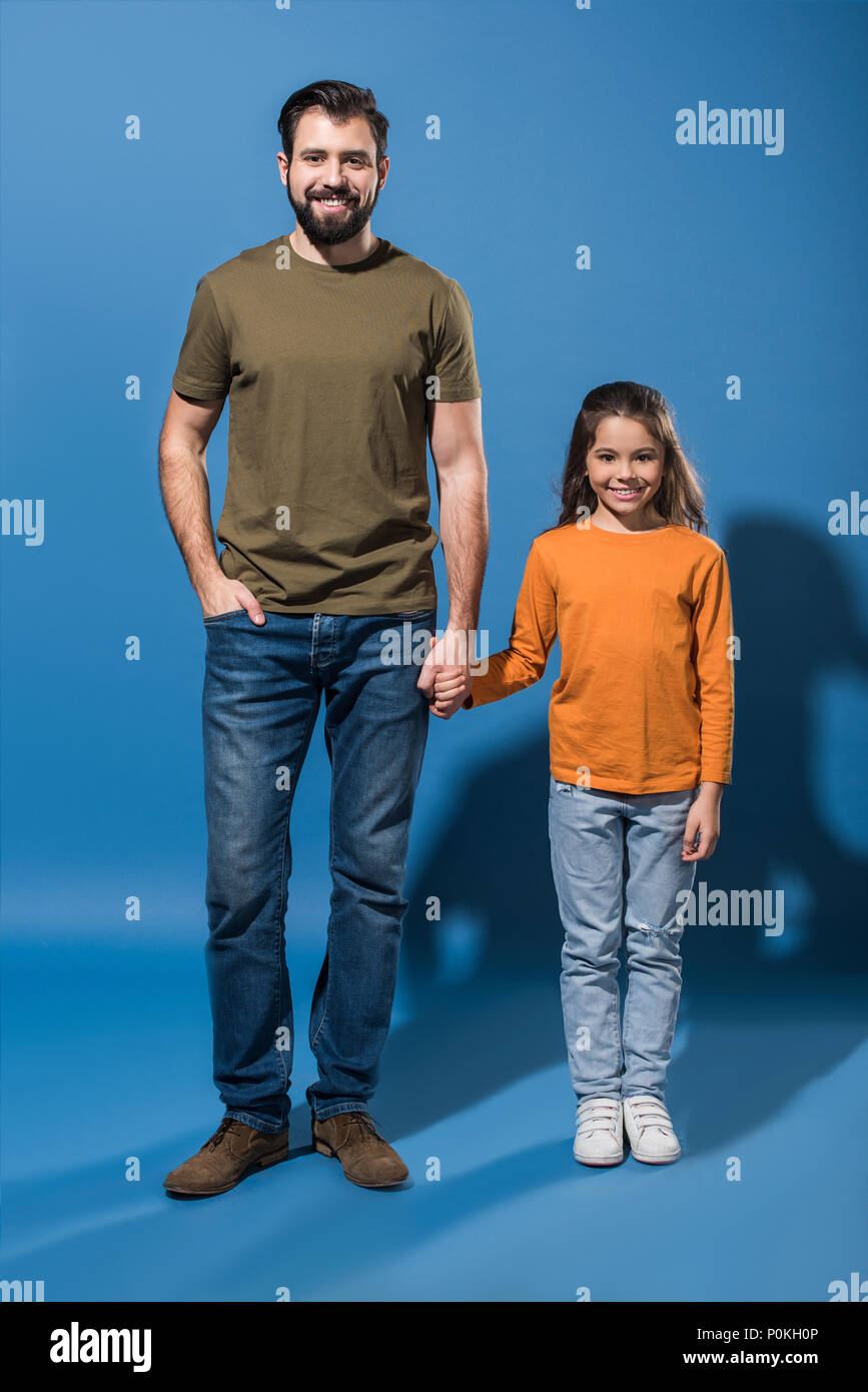 father and daughter standing and holding hands on blue Stock Photo - Alamy