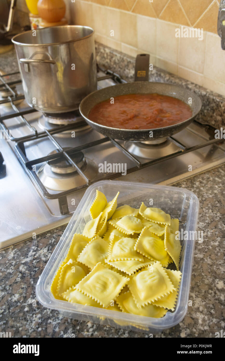 preparing ravioli with tomato sauce on a stovetop Stock Photo