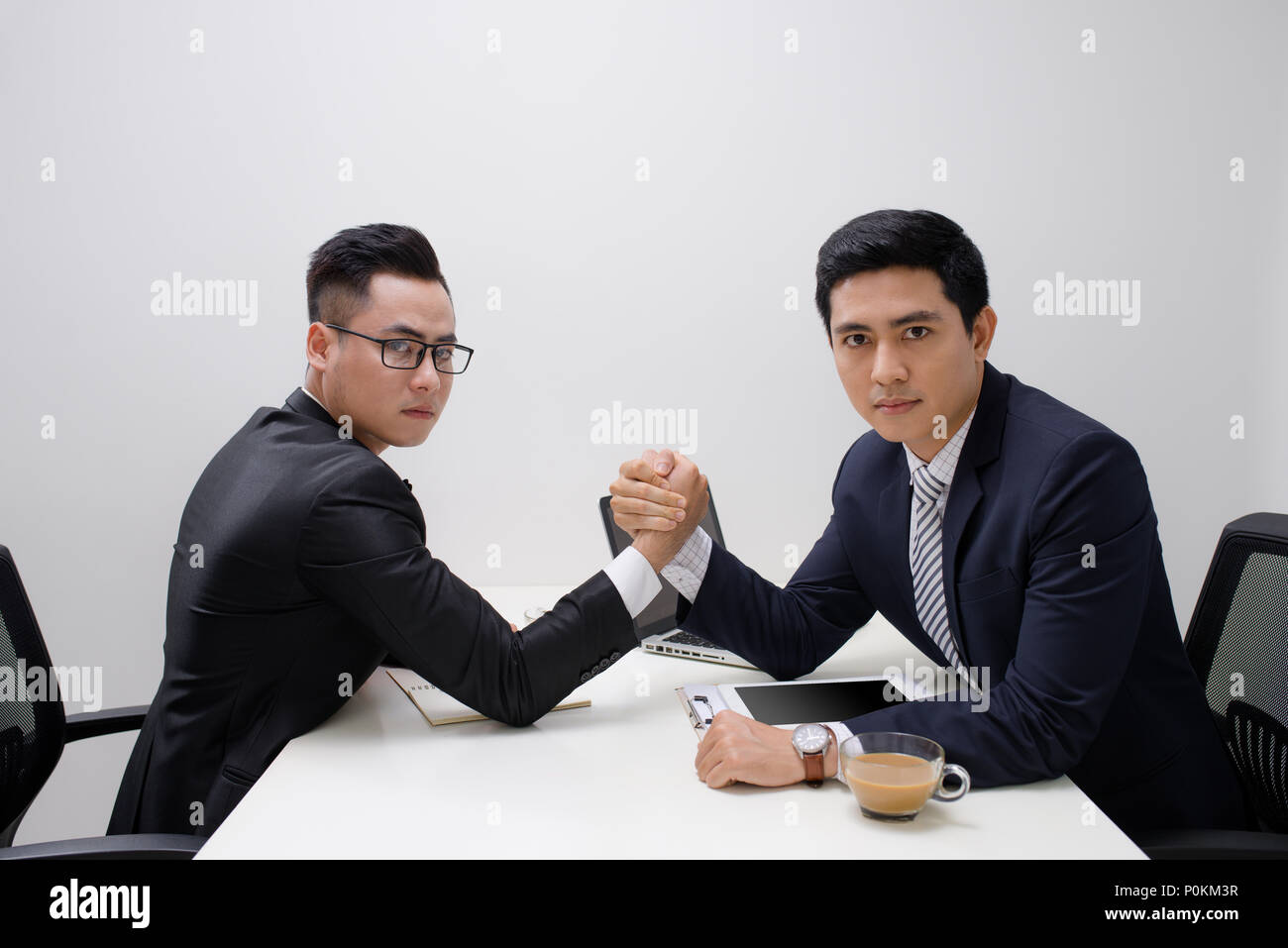 Two businessmen competing arm wrestling in office Stock Photo