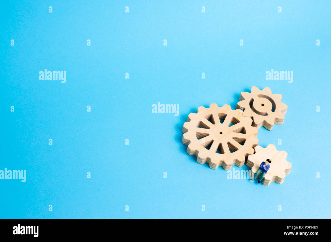 A miniature man is sitting on the gears. The concept of the business process, the generation of ideas and plans. Intellectual investments, innovations Stock Photo