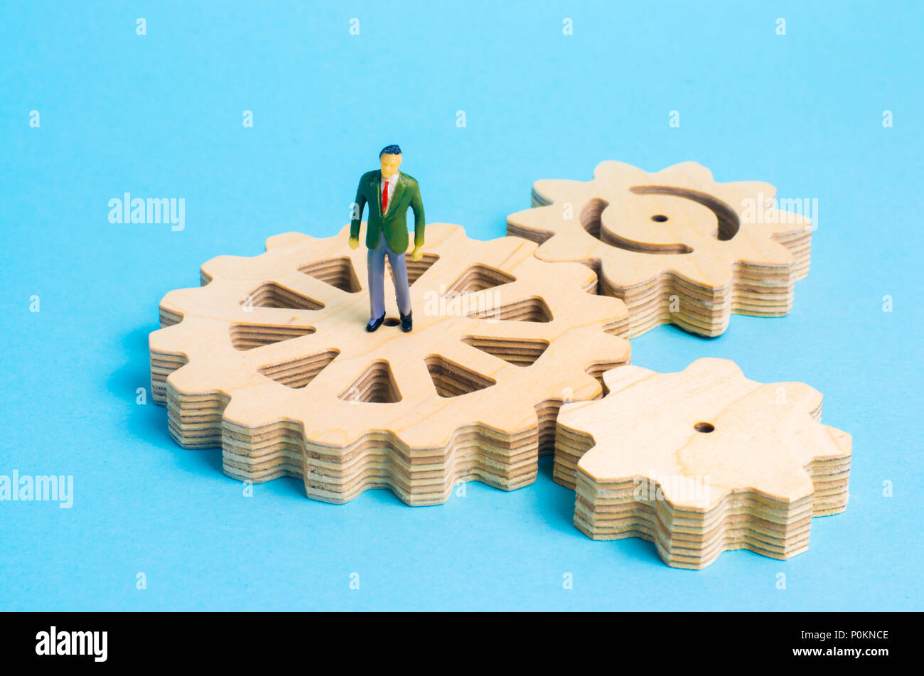 A miniature man is stands on the gears. The concept of the business process, the generation of ideas and plans. Intellectual investments, innovations. Stock Photo
