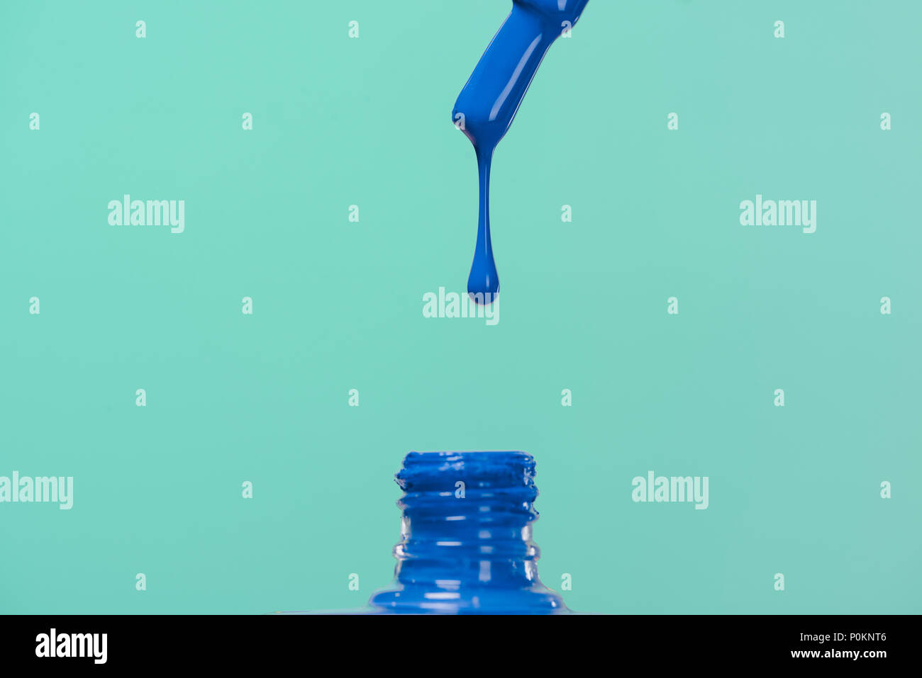 nail polish pouring down into bottle isolated on blue Stock Photo