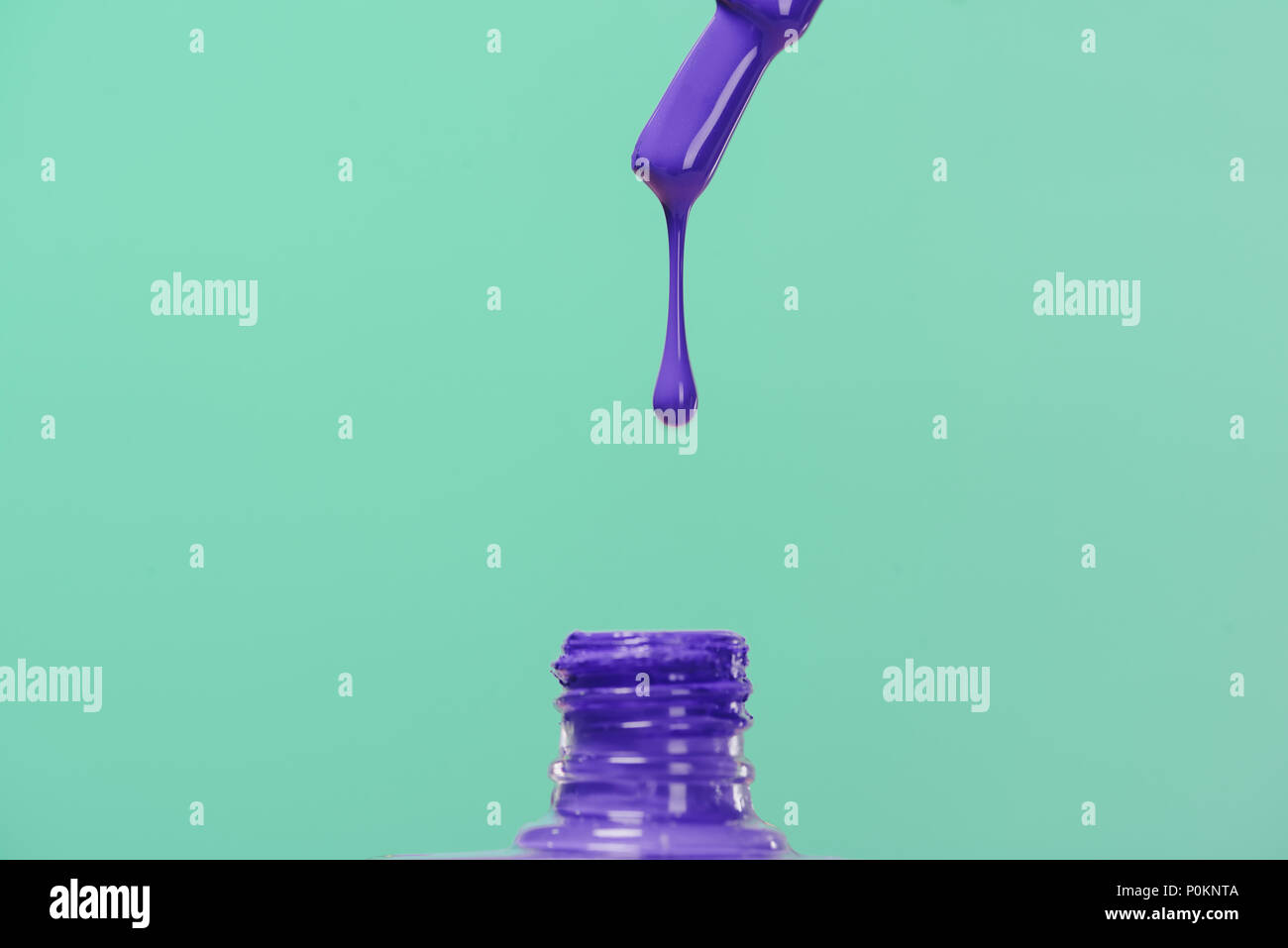 nail polish pouring down into bottle isolated on turquoise Stock Photo