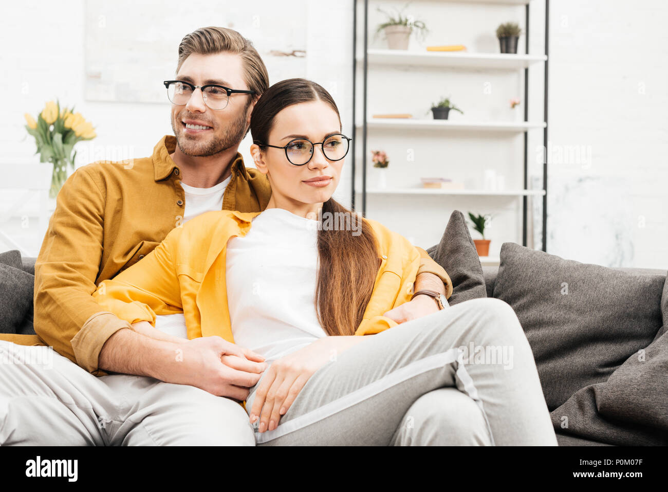 Young Happy Couple Relaxing On Comfy Couch At Home Stock Photo