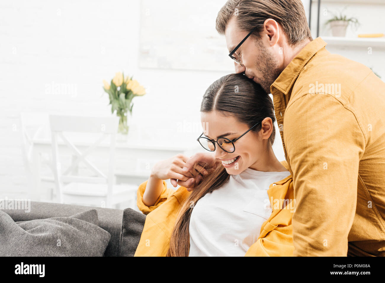man embracing his girlfriend on couch at home Stock Photo Alamy