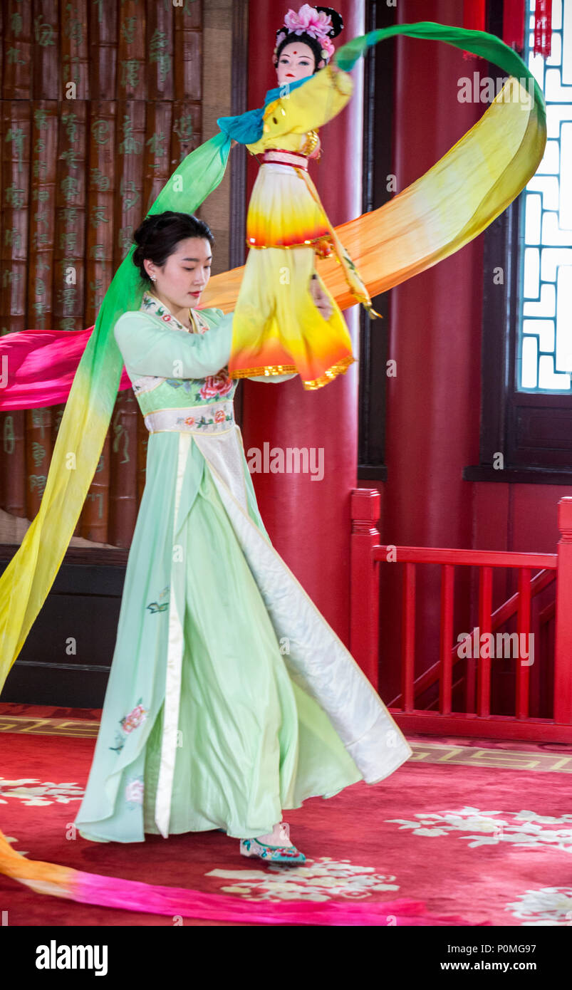 Yangzhou, Jiangsu, China.  Young Woman Performing Traditional Dance with Doll and Swirling Fabric, Slender West Lake Park. Stock Photo