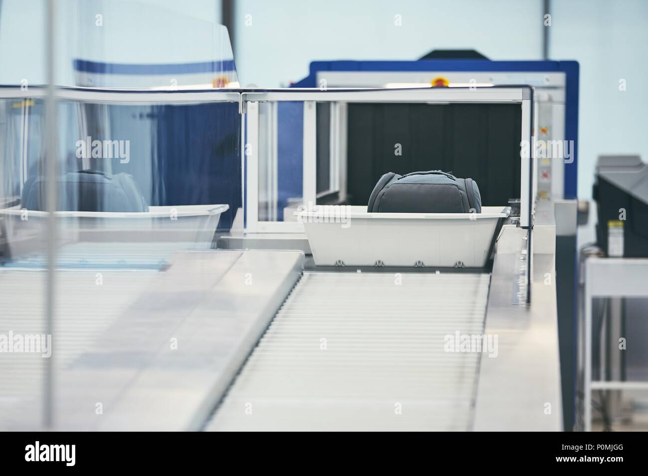 Airport security check. Containers with luggage on conveyor belt after x-ray control. Stock Photo