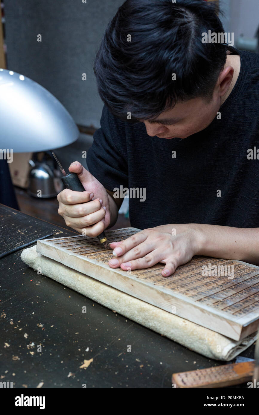 Yangzhou, Jiangsu, China.  China Block Printing Museum.  Calligrapher Carving Chinese Characters into Wood Block. Stock Photo