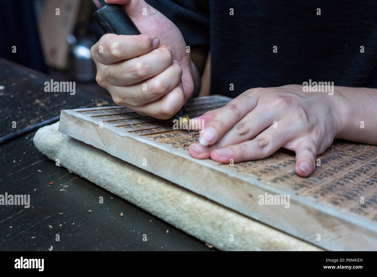 Yangzhou, Jiangsu, China.  China Block Printing Museum.  Calligrapher Carving Chinese Characters into Wood Block. Stock Photo