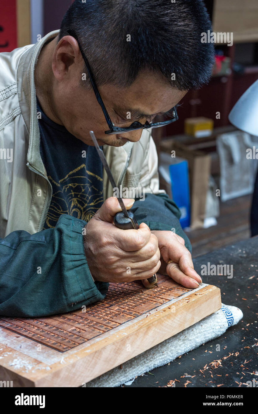 Yangzhou, Jiangsu, China.  China Block Printing Museum.  Calligrapher Carving Chinese Characters into Wood Block. Stock Photo