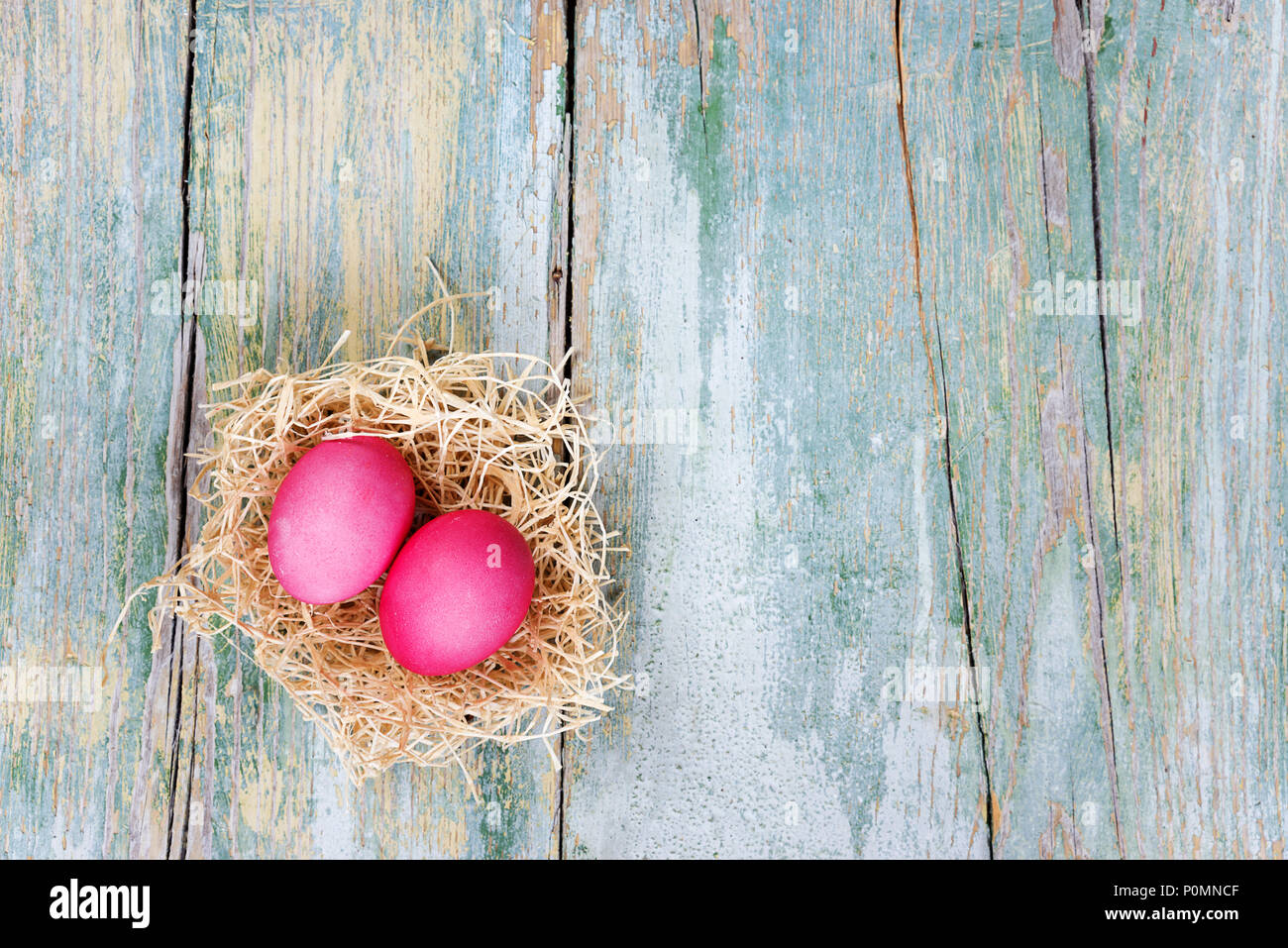 Easter composition with two red eggs in nest on the old blue wooden background, with copy-space, top view Stock Photo