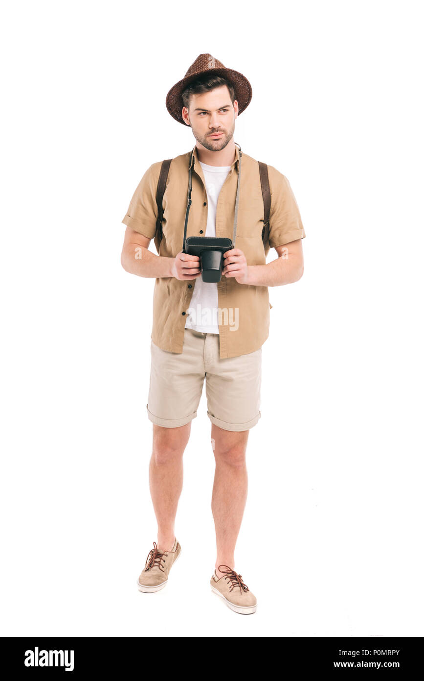full length view of handsome young traveler holding camera and looking ...