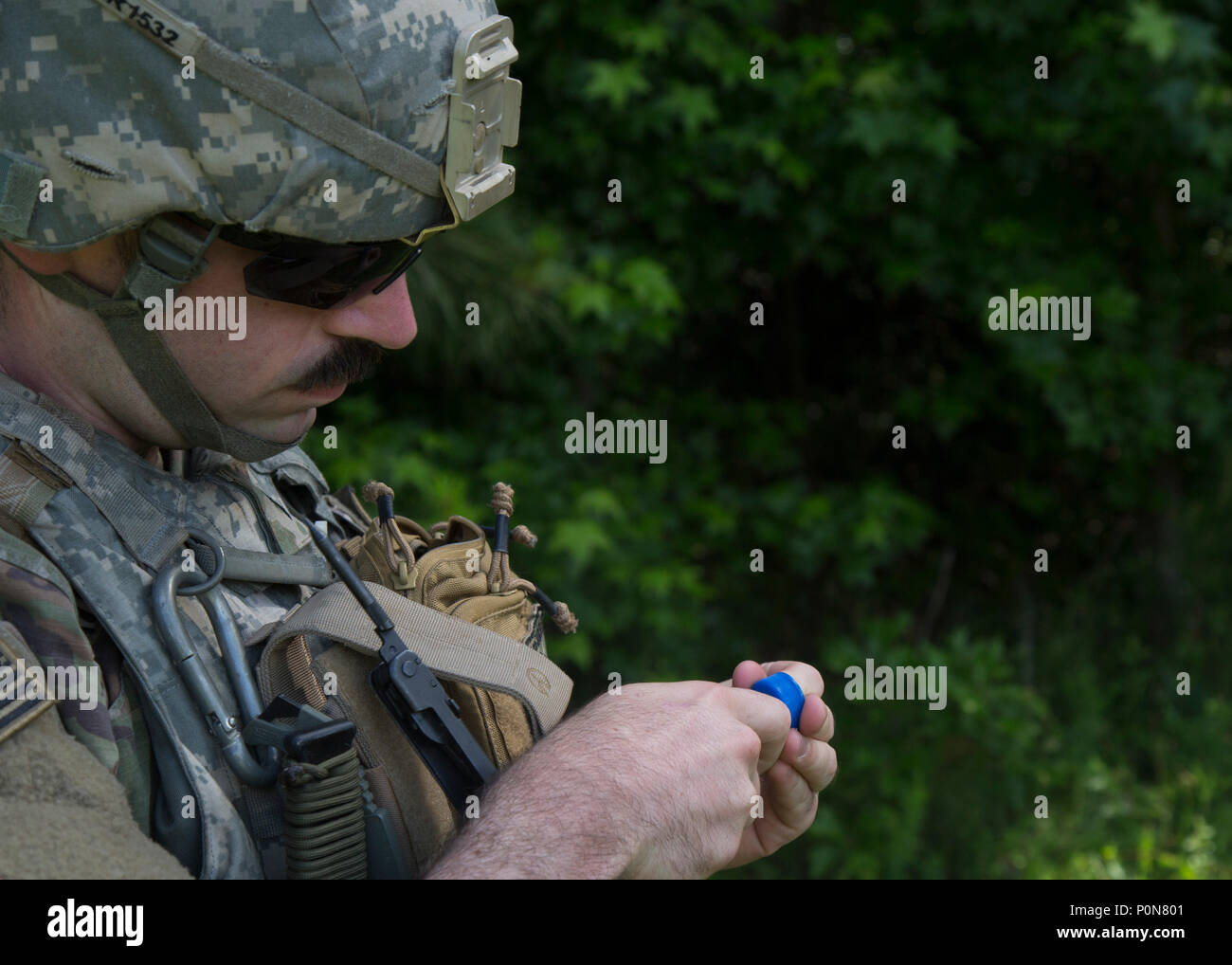 Spc. Matthew Ruben, an explosive ordnance disposal team member with 718th Ordnance Company from Baunholder, Germany, feeds a line of detination cord through a water bottle cap during the 2018 Ordnance Crucible at Fort A.P. Hill, Va., June 5, 2018. EOD (Explosive Ordnance Disposal) teams are assessed on operations and associated tasks required to provide EOD support to unified land operations to eliminate and/or reduce explosive threats . The Ordnance Crucible is designed to test Soldiers' teamwork and critical thinking skills as they apply technical solutions to real world problems improving r Stock Photo