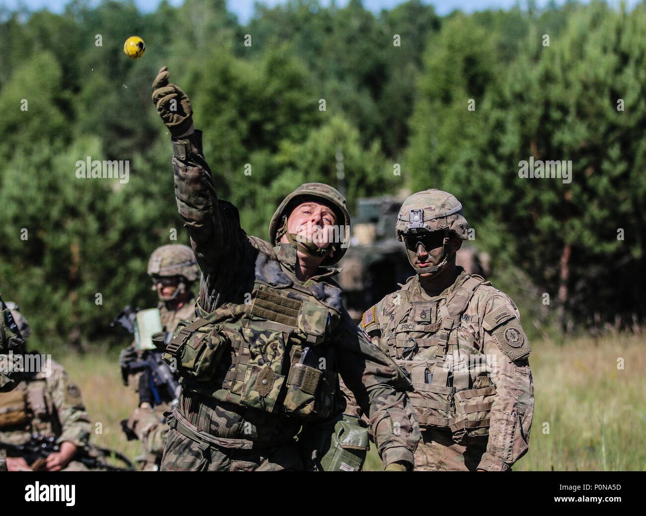 U.S. Army Staff Sgt. Mitchel Price (right), Little Chute, Wisconsin native, squad leader with 1st Squadron, 2nd Cavalry Regiment, and Polish army Pvt. Luckasz Wons, with 15th Mechanized Brigade, throw training grenades during Puma 2 Exercise as a part of Saber Strike 18 with Battle Group Poland at Wyreby, Poland on June 7, 2018. This year's exercise, which runs from June 3-15, tests allies and partners from 19 countries on their ability work together to deter aggression in the region and improve each unit's ability to perform their designated mission. (U.S. Army photo by Spc. Hubert D. Delany  Stock Photo