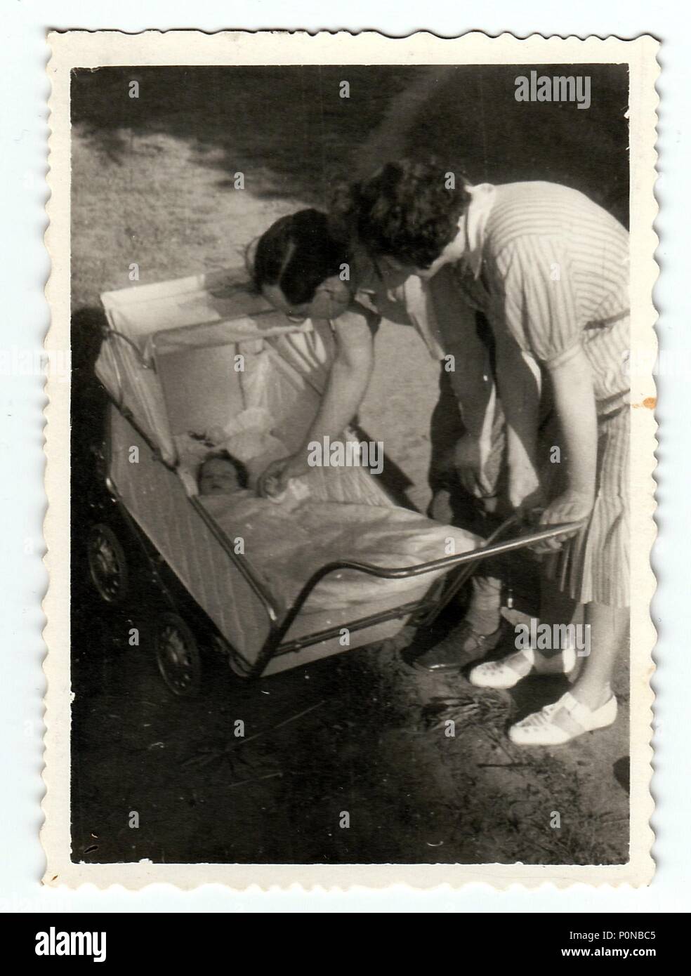 HODONIN, THE CZECHOSLOVAK REPUBLIC, CIRCA 1940: Vintage photo shows baby girl in a pram (baby carriage) with parents, circa 1940. Stock Photo