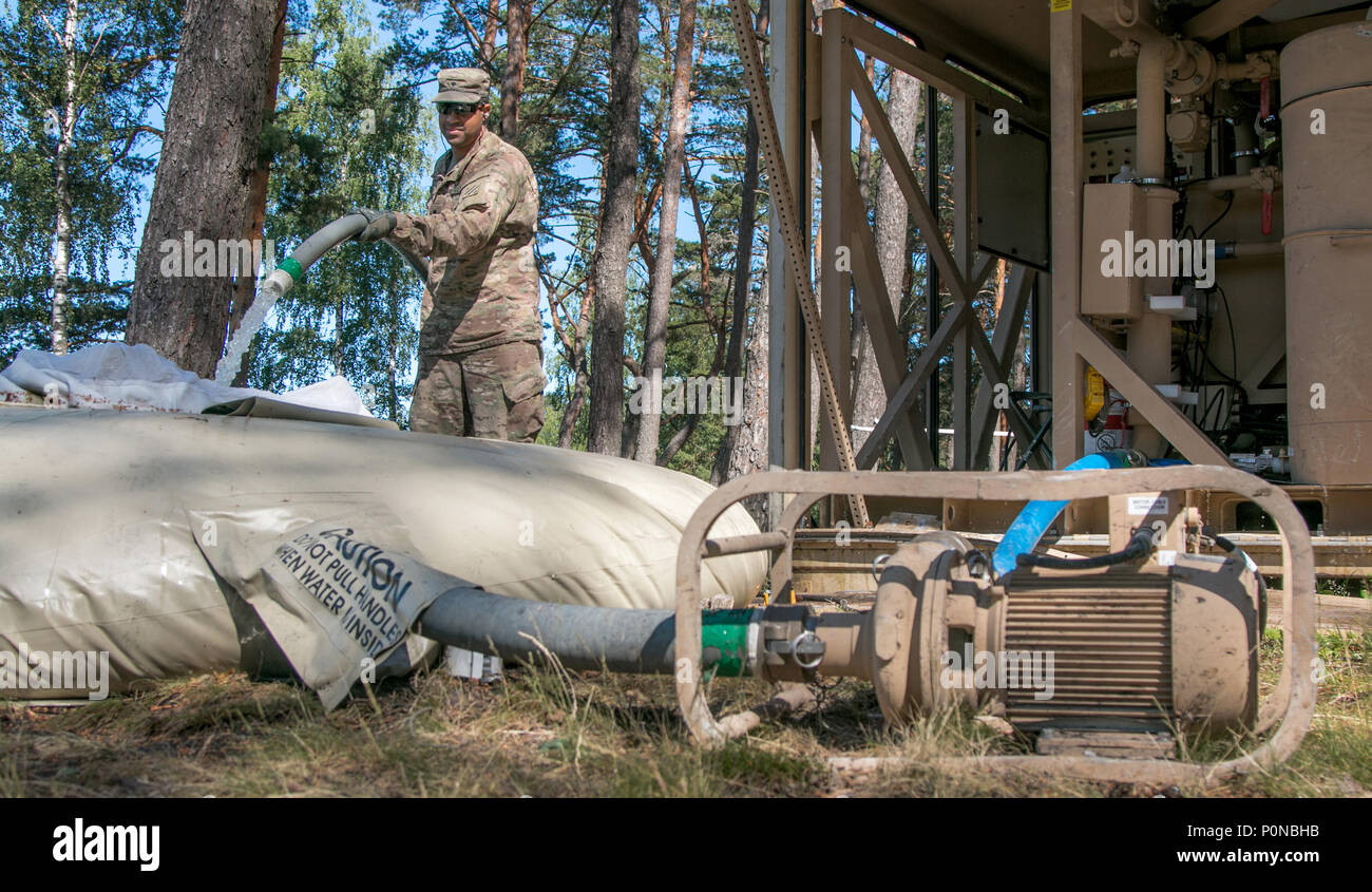 Spc. Manuel Otero, a water treatment specialist assigned to 226th Composite Supply Company, 87th Combat Sustainment Support Battalion, 3rd Infantry Division, Fort Stewart, Georgia, fills a water storage blivet with lake water during Saber Strike 18 on Adazi base, Latvia, June 6, 2018. Saber Strike is a multinational exercise currently in its eighth year. This year's exercise is scheduled to run from June 3-15 and provides the opportunity for participants from 19 countries to train together and improve each units ability to perform their designated missions. (U.S. Army photo by Spc. Dustin D. B Stock Photo