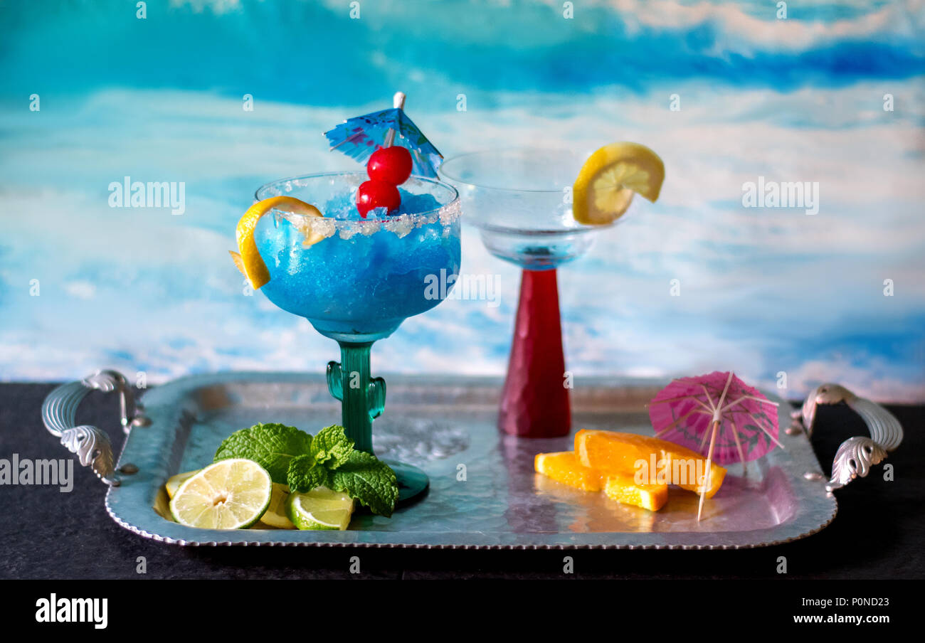 A colorful blue frozen cocktail with cherry and lemon garnish. One drink is never enough Stock Photo