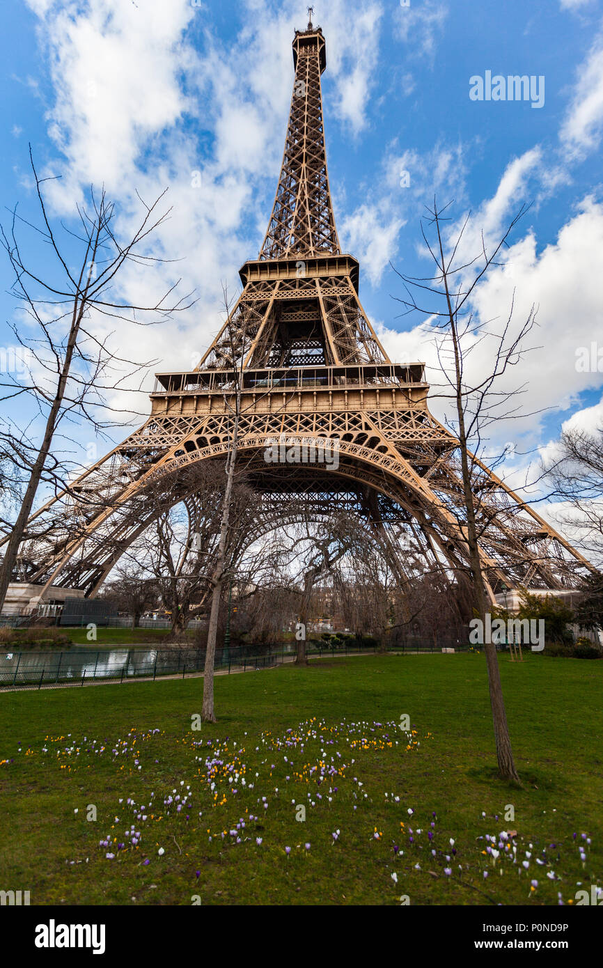 Wide angle view of iconic Eiffel tower with dramatic cloudy blue sky in the background. Stock Photo