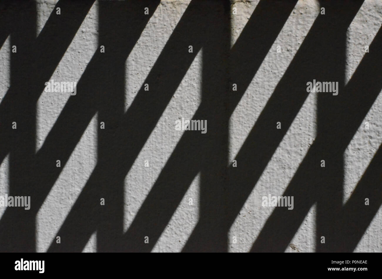 Abstract pattern formed by the shadow odf a fireescape on a grey wall ...