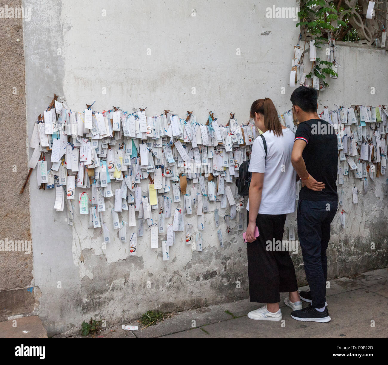 Suzhou, Jiangsu, China.  Couple Examining Tags Containing Hopes for Good Wishes, left by Passersby.  Shantang District. Stock Photo