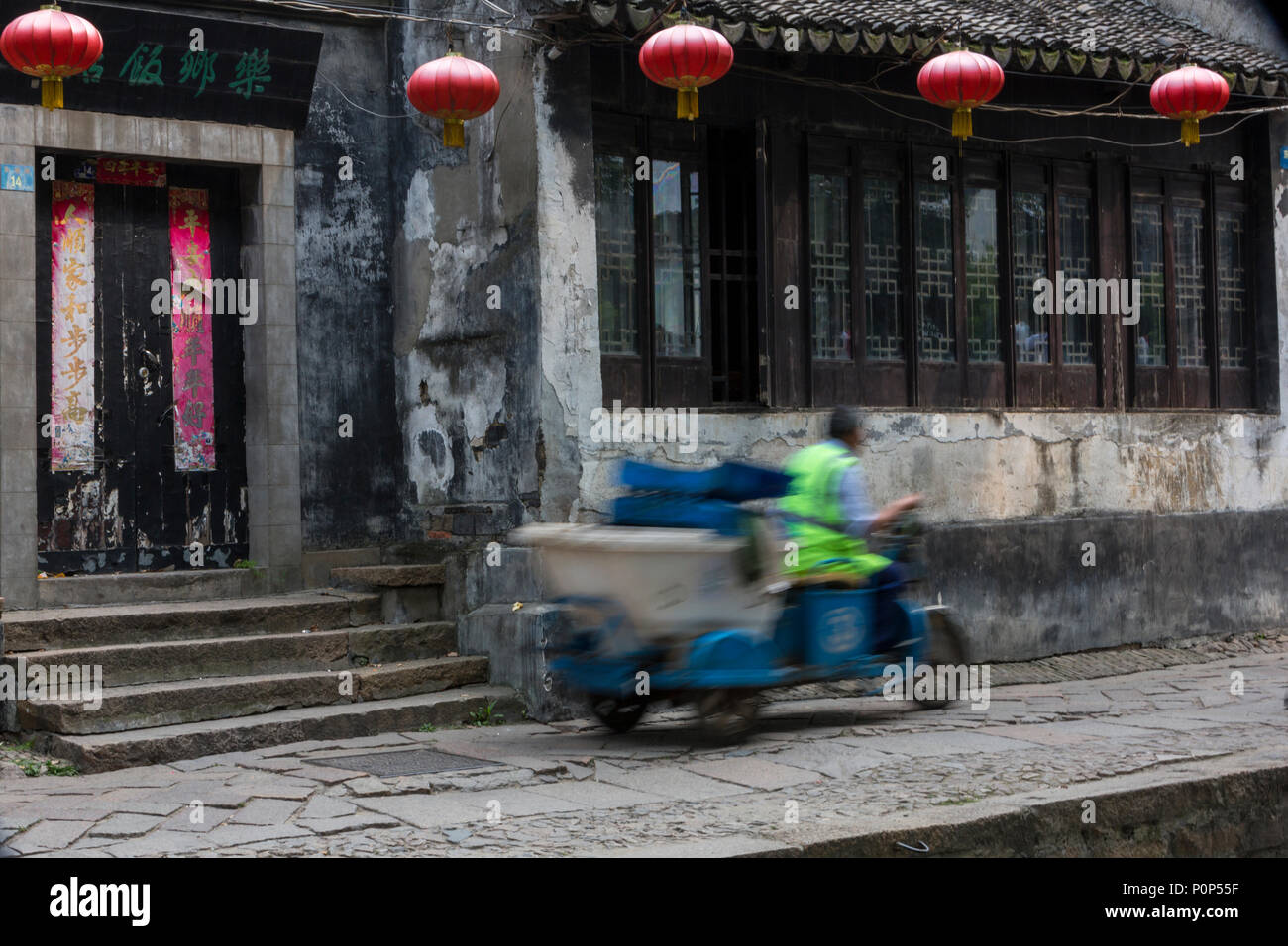 Suzhou, Jiangsu, China.  Three-wheeled Goods Transporter Speeds through Tongli Ancient Town near Suzhou. Stock Photo