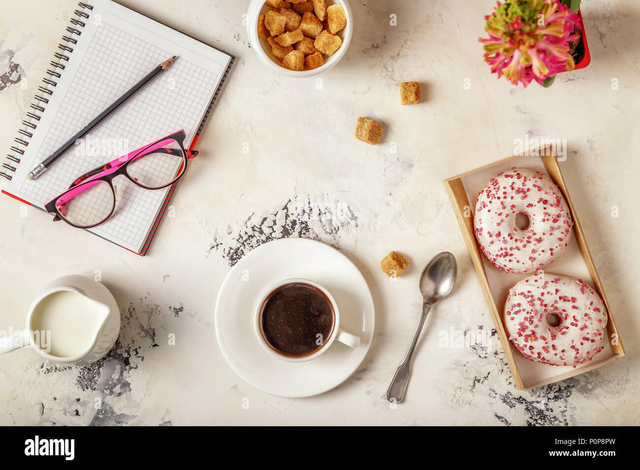 Notepad, donuts and coffee on white table. Top view with copy space. Stock Photo