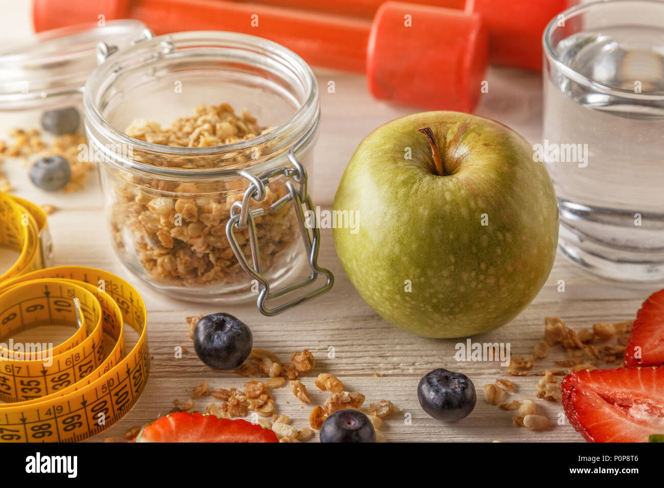 Healthy breakfast, dumbbells and measuring tape on wooden background, selective focus. Stock Photo