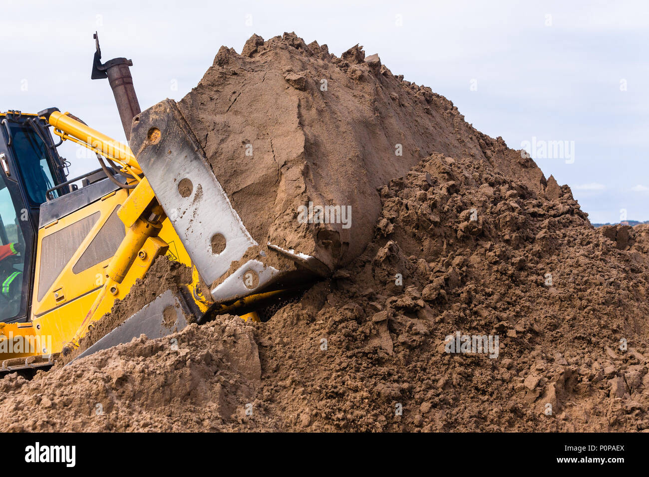 Earthworks construction heavy dozer machine metal scoop bucket pushing sand closeup photo. Stock Photo