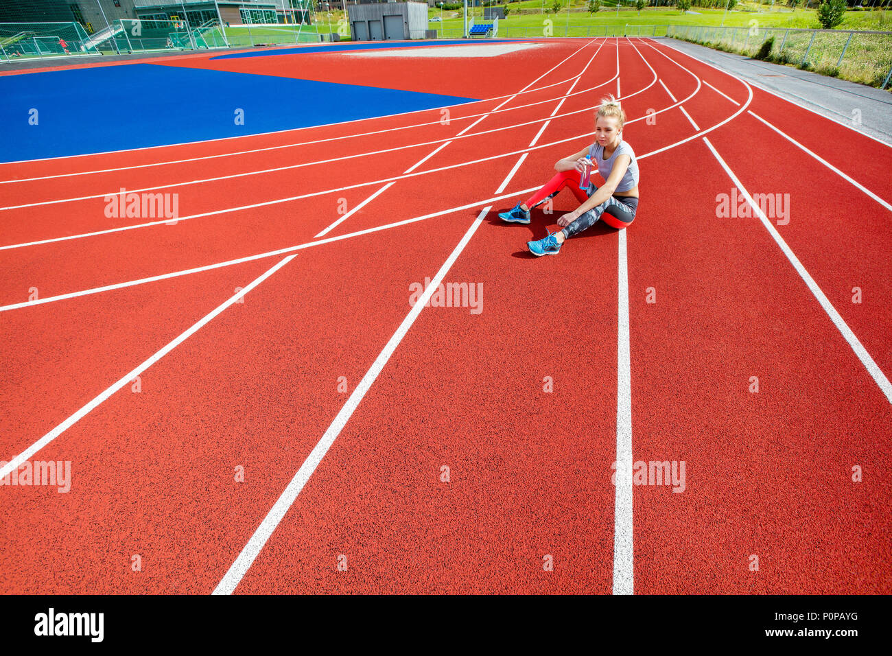 Young Woman Holding Water Bottle On Running Tracks Stock Photo