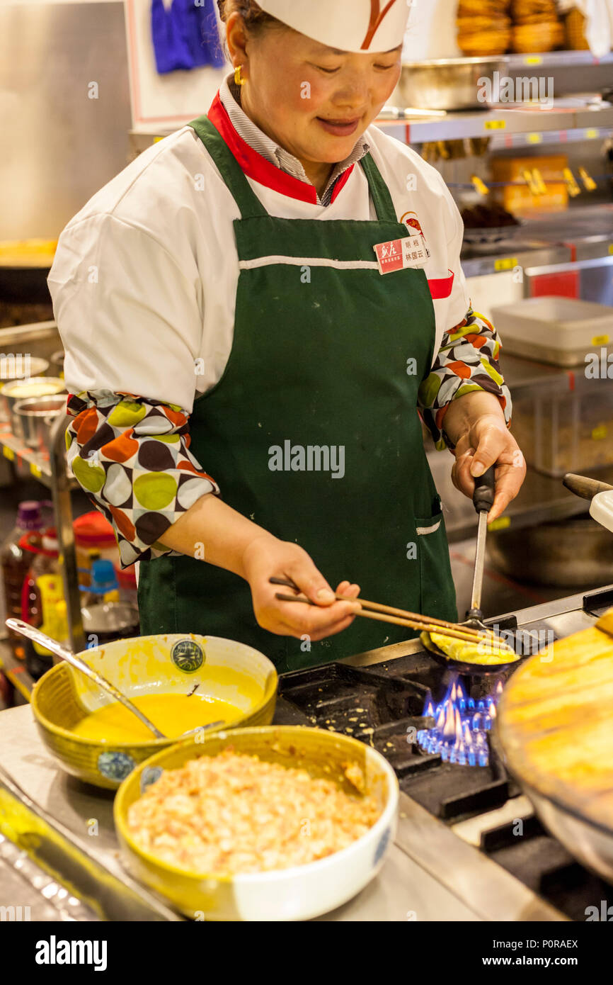Nanjing, Jiangsu, China.  Cook in Restaurant Kitchen Making Egg Dumplings with Pork. Stock Photo