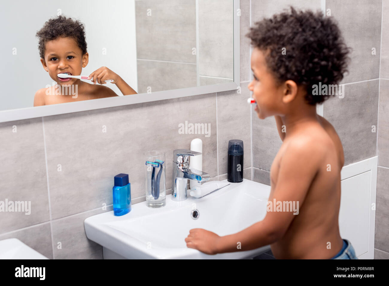 Beautiful African American Kid Brushing Teeth In Bathroom Stock