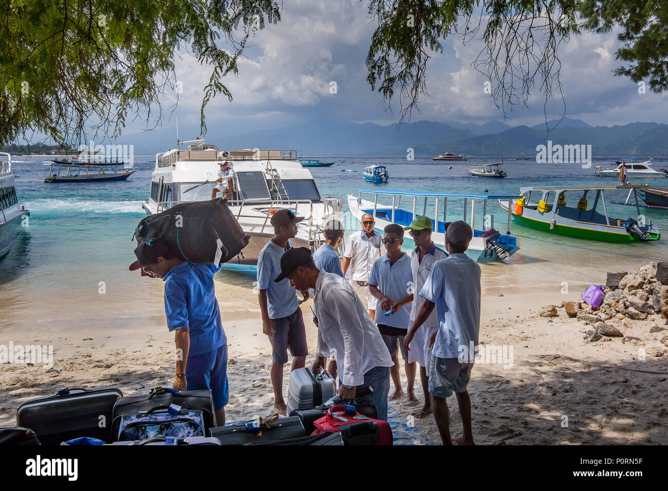 Porters bring suitcases to the beach for transportation by the ferry to Bali. Gili  Trawngan, Indonesia, April 26, 2018 Stock Photo
