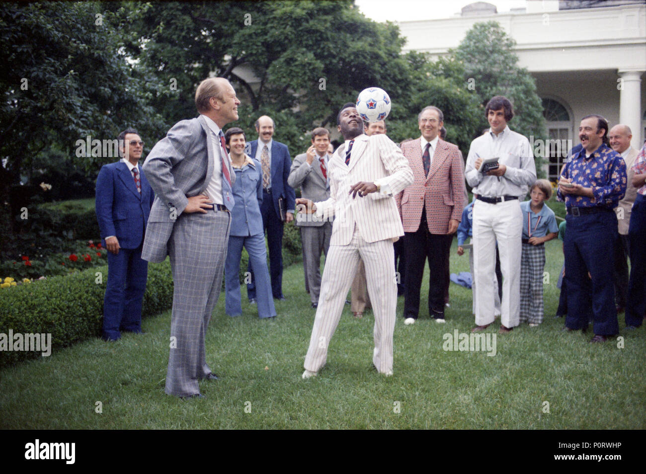 1975, June 28 – Rose Garden – The White House –  Gerald R. Ford, Edson Arantes 'Pele' Nacimento, Amb. Joao Augusto de Araujo Castro, Others – Pele juggling soccer ball on foot and head – Brazilian Soccer Player; Ambassador from Brazil to the U.S. Stock Photo