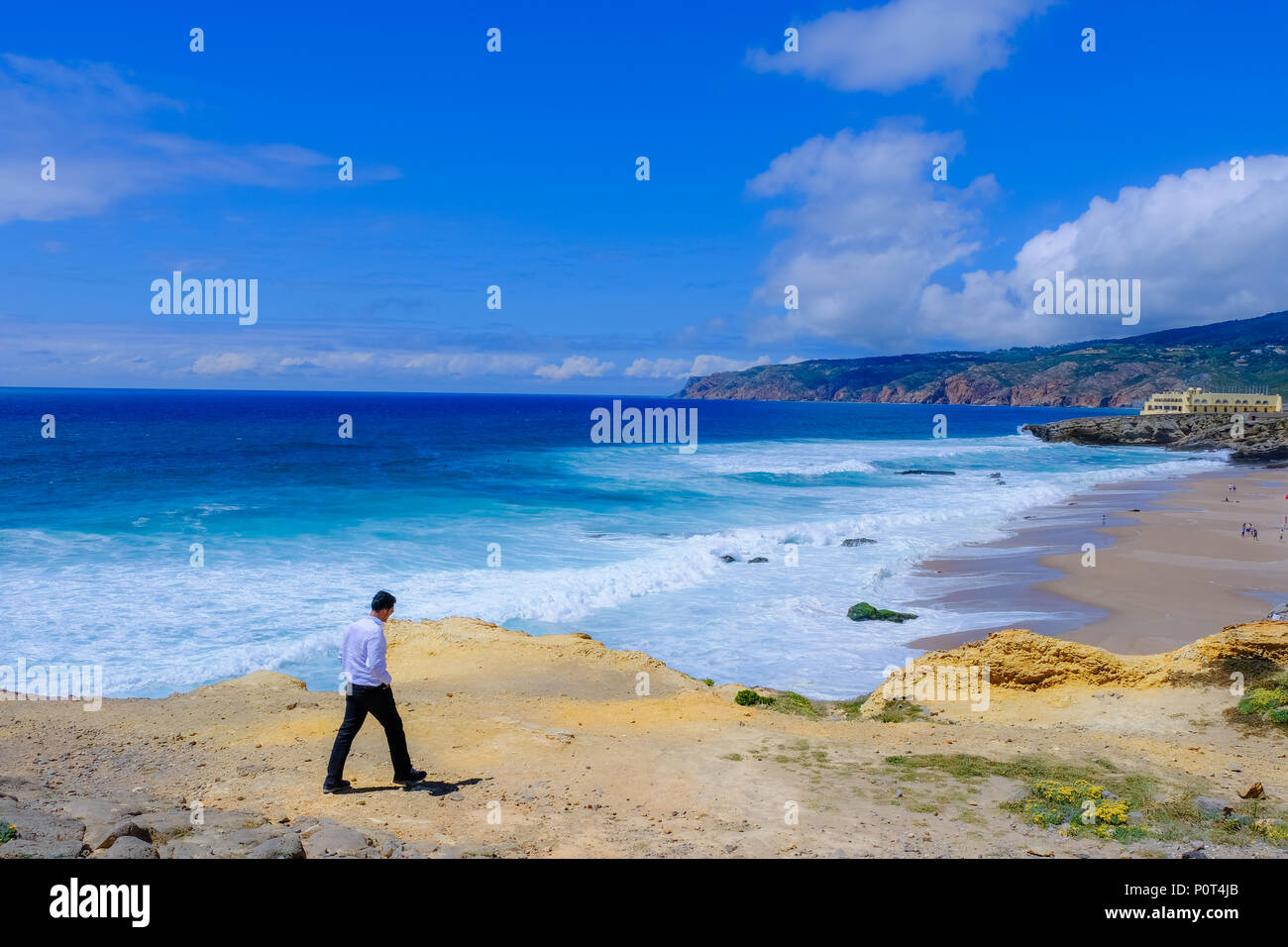 Young man walking along beautiful shore of the Atlantic Ocean in western Portugal during the day Stock Photo