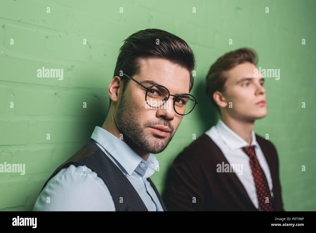 young handsome men in front of green wall Stock Photo - Alamy