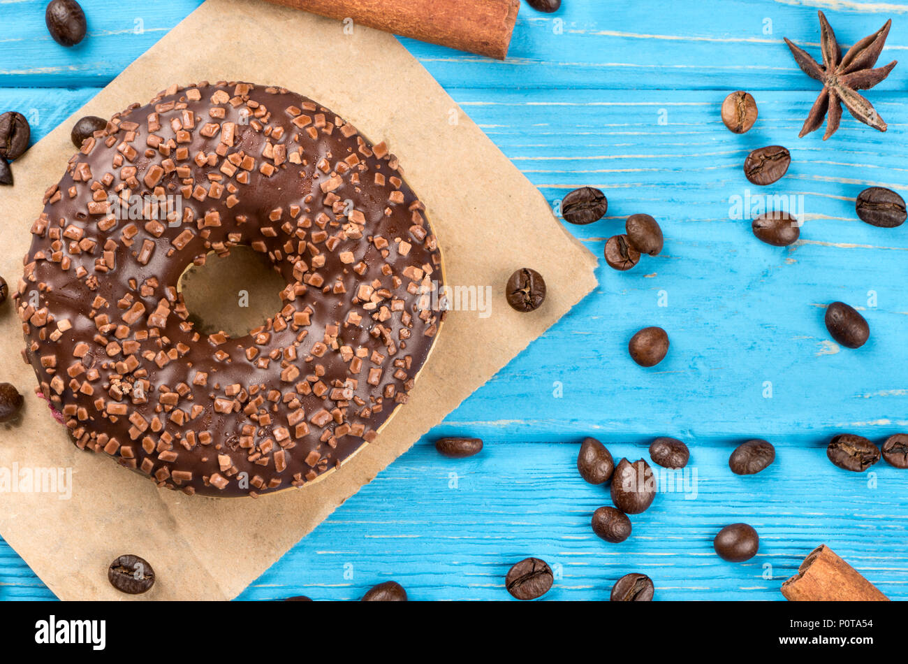 Chocolate donut with scattered grains of coffee and spices on a wooden background, top view Stock Photo