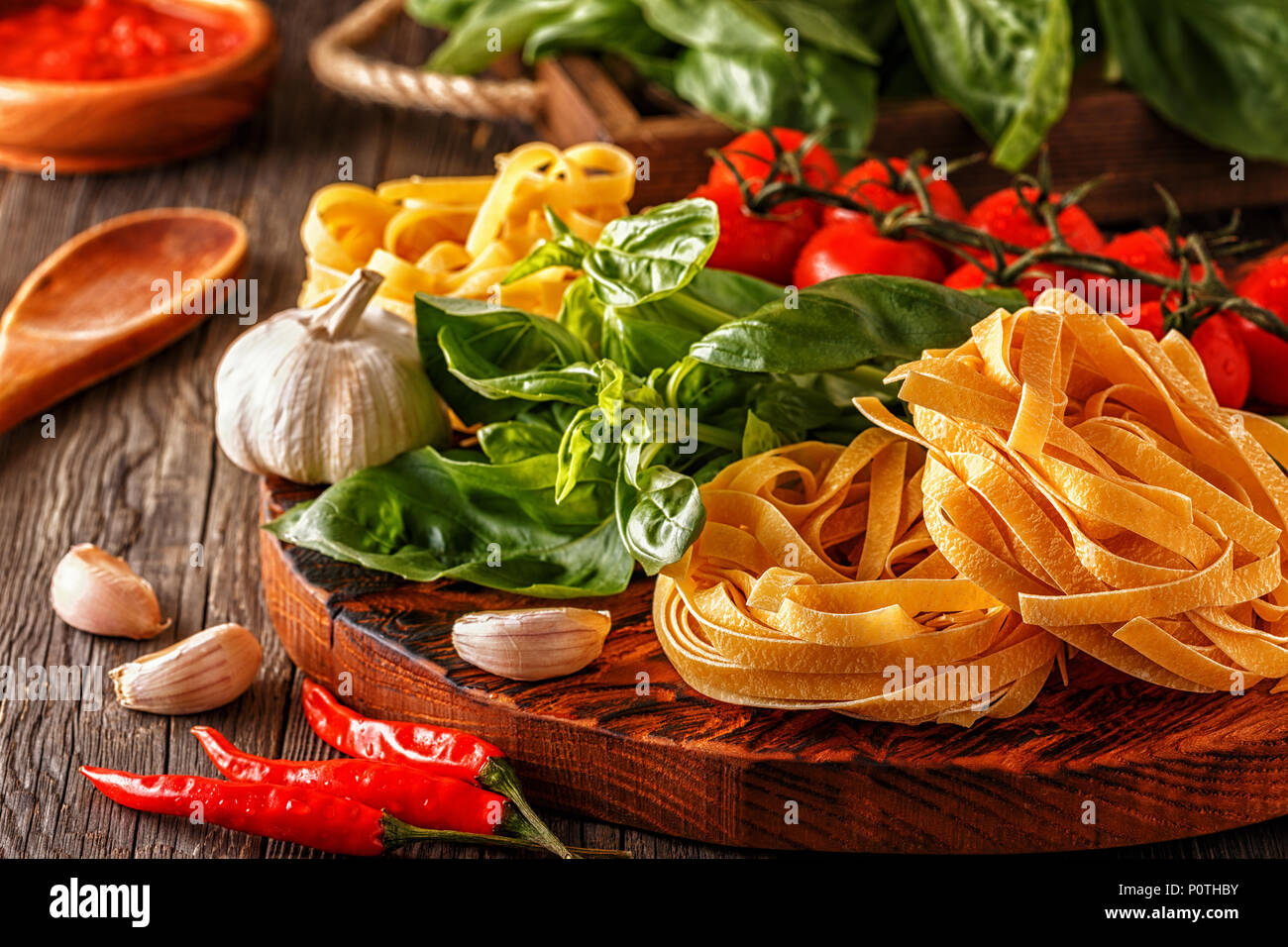 Products for cooking - pasta, tomatoes, garlic, pepper, and basil on the old wooden background. Stock Photo