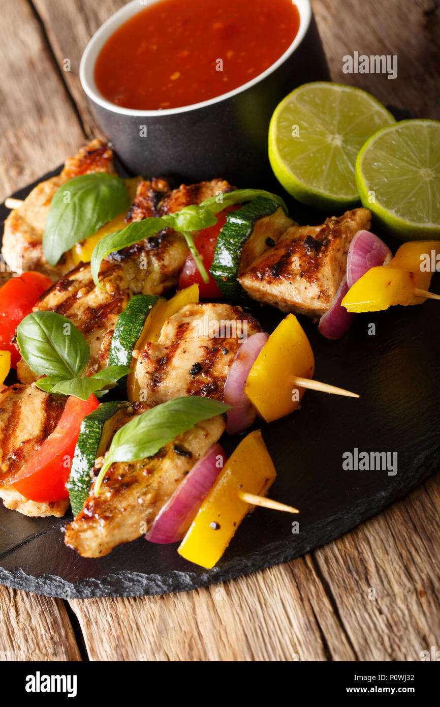 spicy grilled chicken kebabs with vegetables served with ketchup closeup on the table. vertical