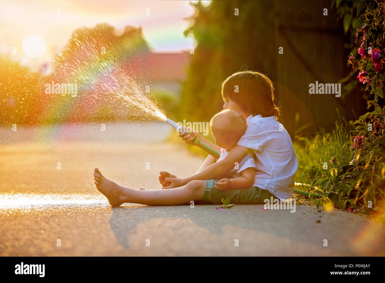 Playing kids water sprinkler backyard hi-res stock photography and ...