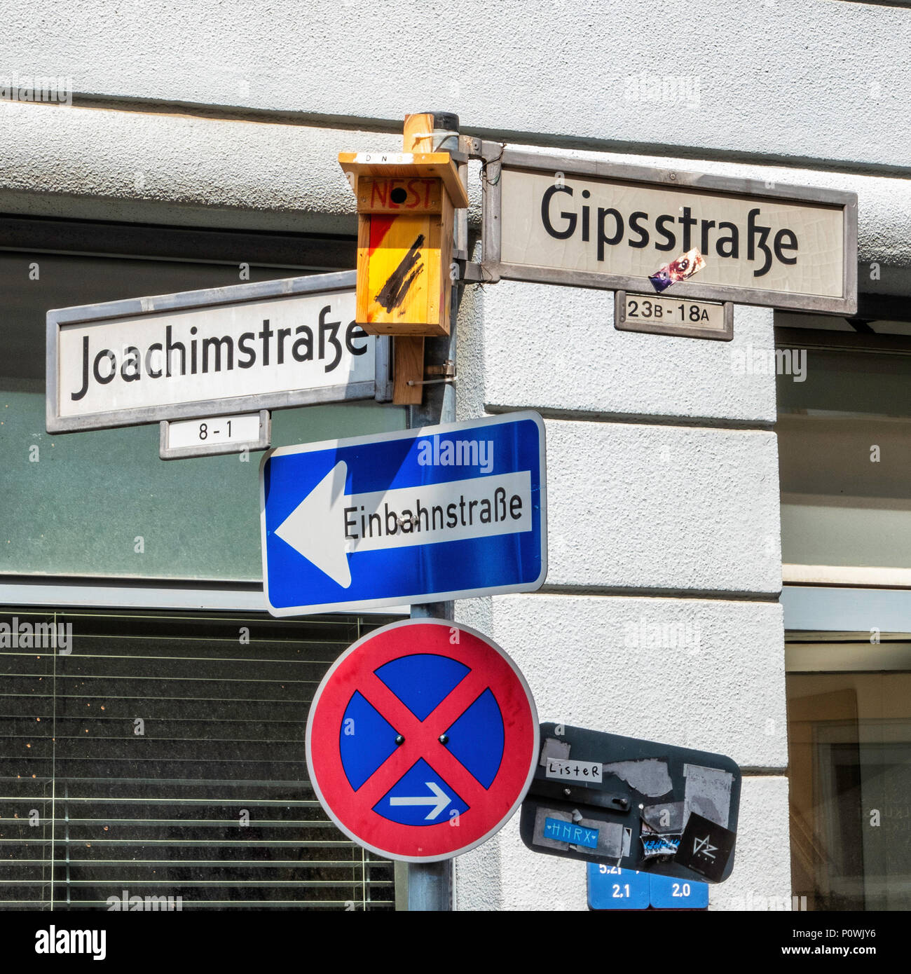 Bird nesting box on a pole with street signs and traffic signs in an urban street in Berlin Stock Photo