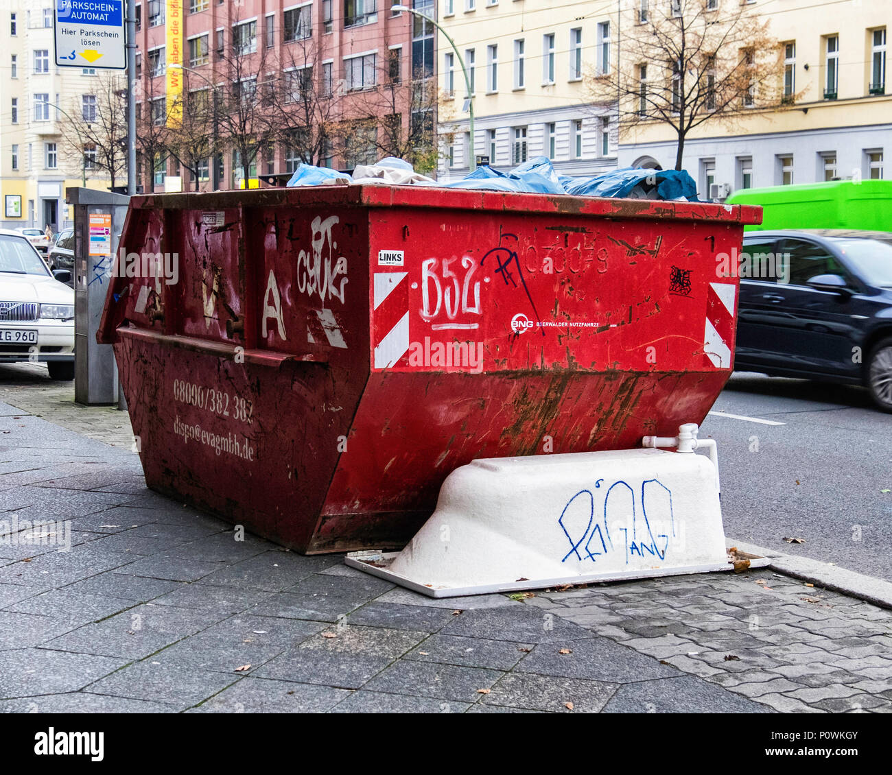 Abandoned bath next to full skip in city street. Trash,garbage,rubbish