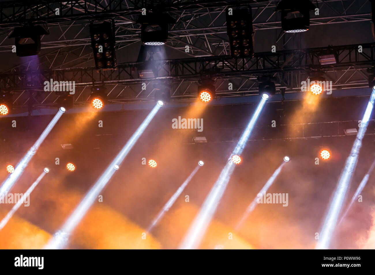 outdoor stage during performance with yellow spotlights and blue searchlights  Stock Photo