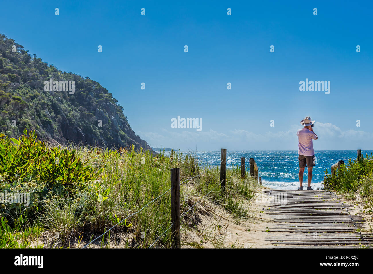 Ma n taking a photo with his phone on Zenith Beach, Port Stephens, NSW, Australia Stock Photo