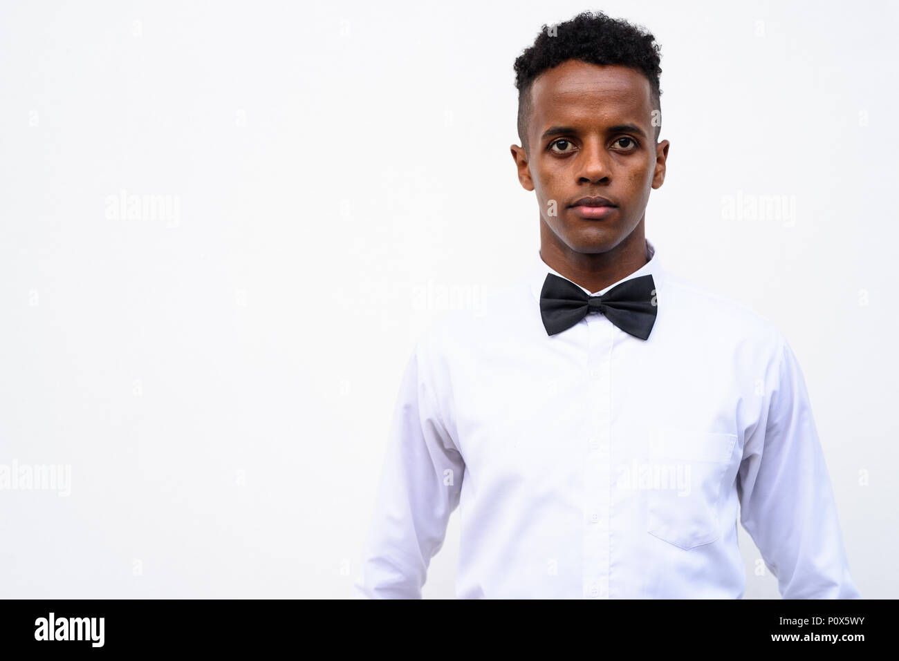 Young handsome African businessman wearing bow tie against white Stock Photo