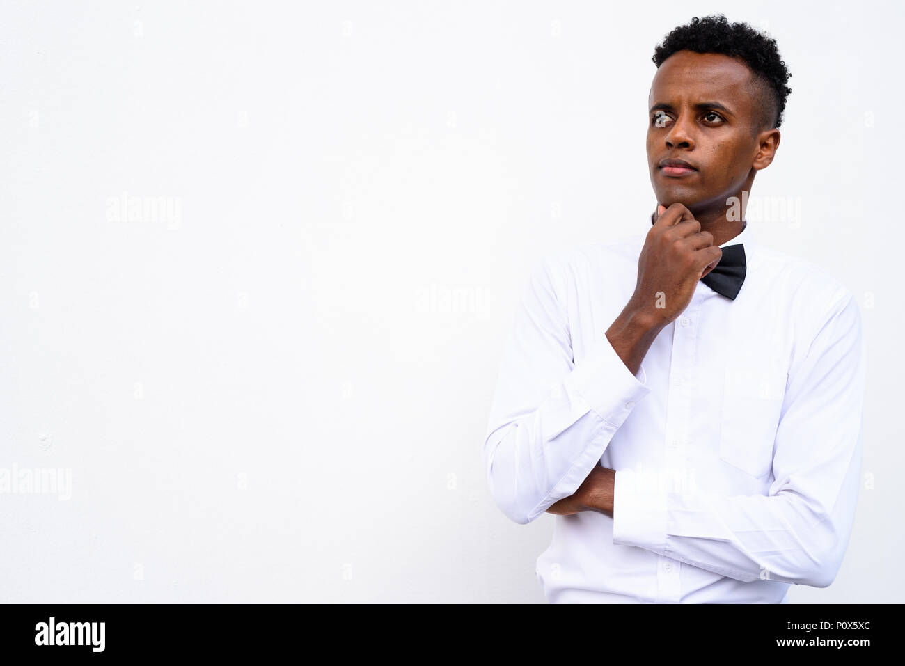 Young handsome African businessman wearing bow tie against white Stock Photo